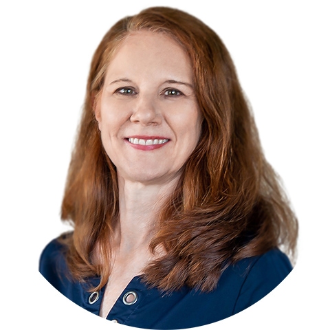 Woman with shoulder-length auburn hair wearing a navy blue top, posed against a plain white background, presenting a professional and approachable demeanor