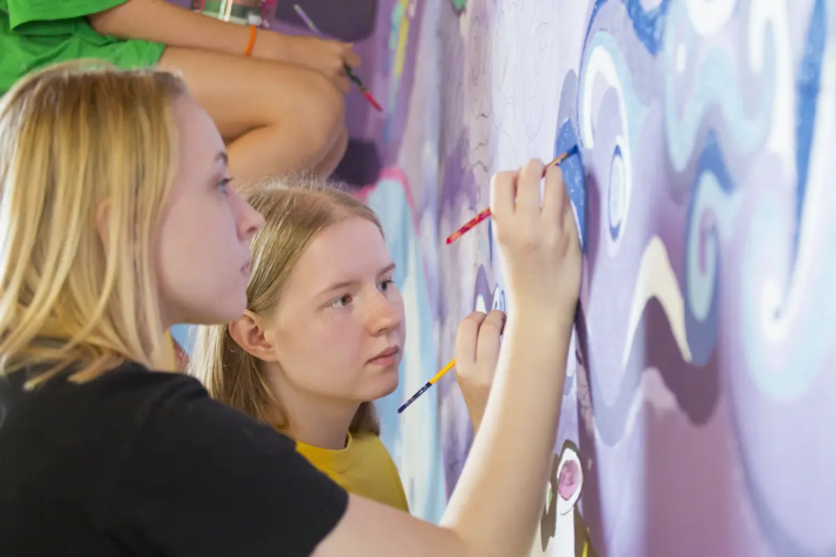 teenage girls painting a mural