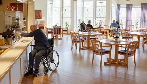 senior living cafeteria with man in wheelchair getting food