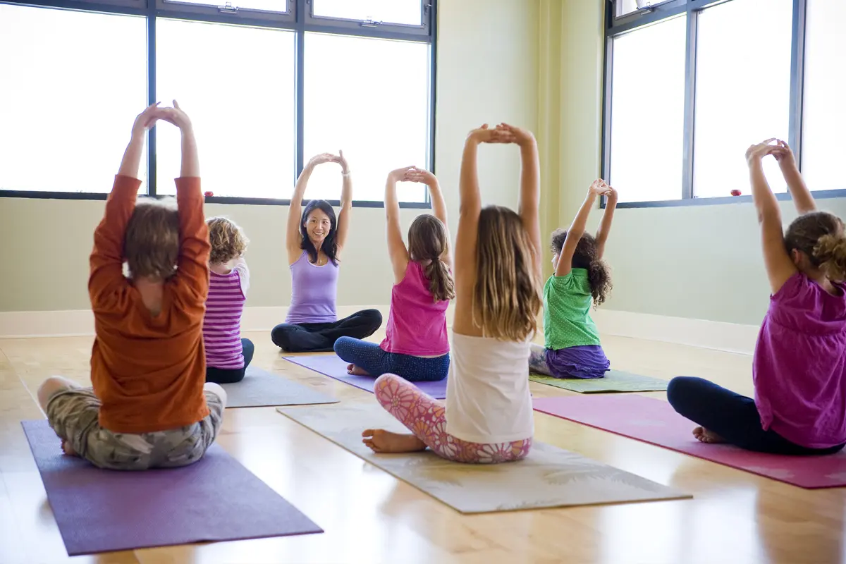 group of adults and children outside doing yoga