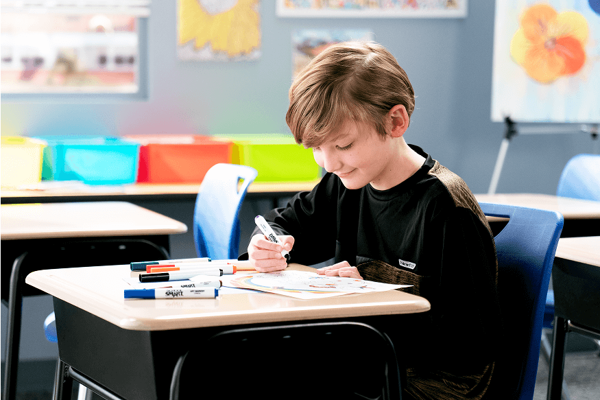 Child drawing with colorful markers at a desk